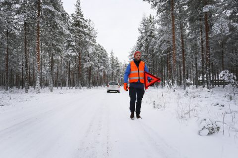 Autoilija vie varoituskolmion varoittamaan muuta liikennettä.